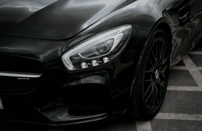 Чёрный автомобиль крупным планом — фара и колесо